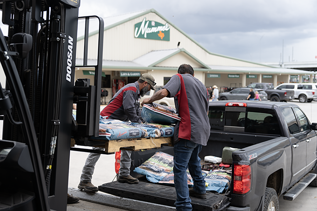 Mumme's staff loading bagged feed into a customer's truck outside the Hondo store