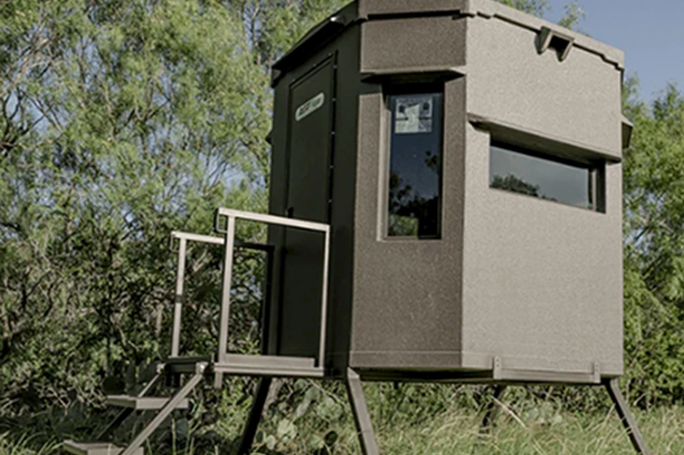 An All Seasons tower blind on stands in the South Texas brush, with stairs and a rail
